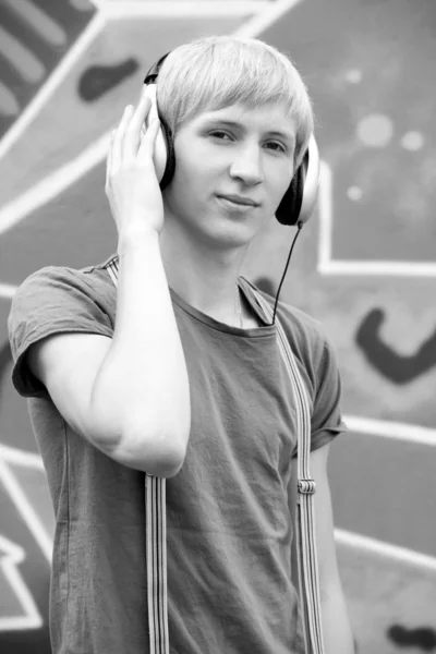 Style teen boy with headphones near graffiti background. — Stock Photo, Image
