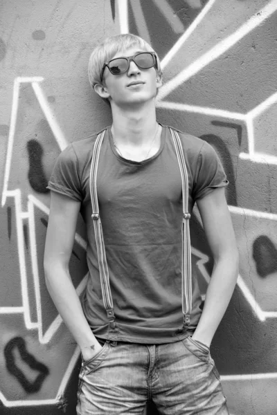 Stil teen pojke med solglasögon nära graffiti bakgrund. — Stockfoto