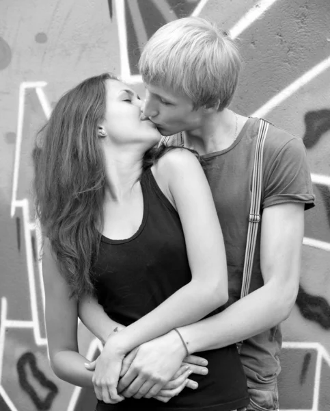 Młoda para całuje w pobliżu graffiti tło. — Zdjęcie stockowe