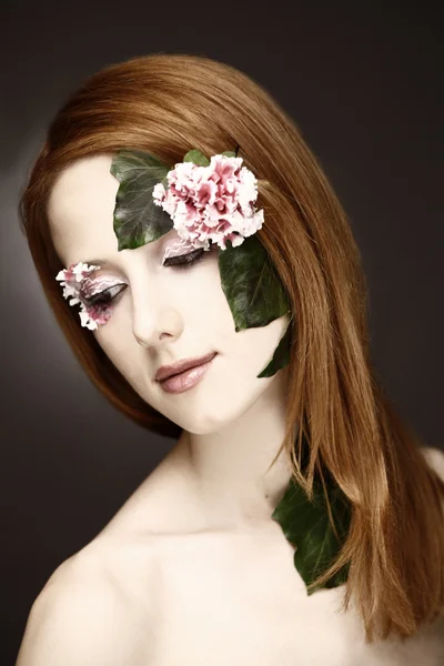 Portret van roodharige meisje met bloem en make-up. — Stockfoto