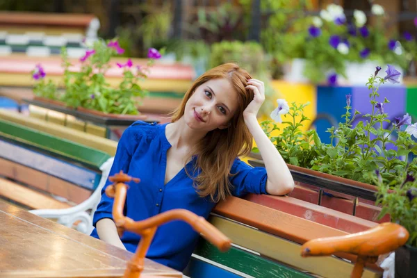 Style rödhårig flicka sitter på bänken i caféet — Stockfoto