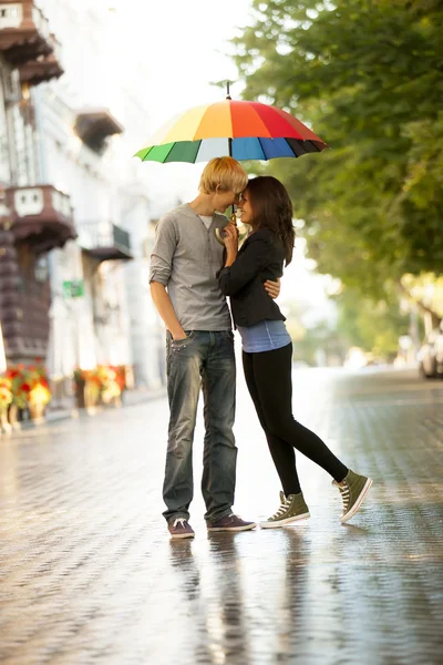 Молодая пара на улице города с зонтиком — стоковое фото