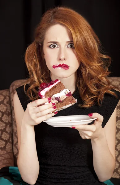 Rödhårig tjej i hemlighet äta kakan. — Stockfoto