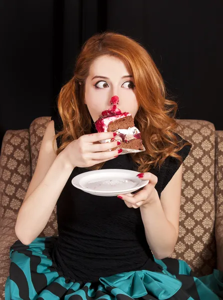 Redhead girl secretly eating cake. — Stock Photo, Image
