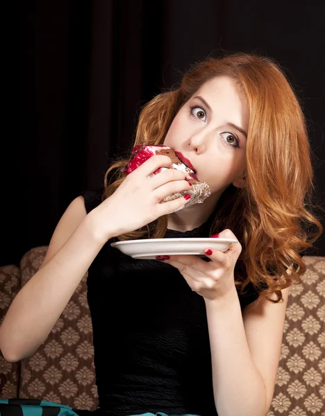 Redhead girl secretly eating cake. — Stock Photo, Image