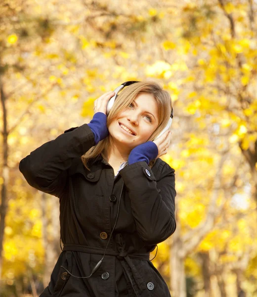 Menina com fones de ouvido no parque de outono . — Fotografia de Stock