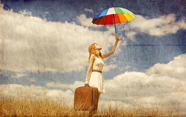 Schöne rothaarige Mädchen mit Regenschirm und Koffer im Freien. — Stockfoto