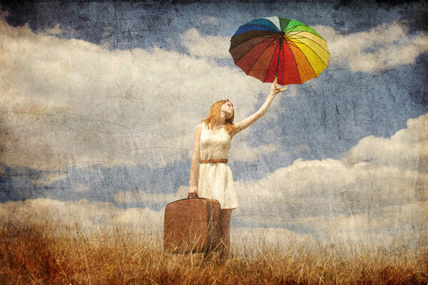 Красивая рыжая девушка с зонтиком и чемоданом на открытом воздухе
.