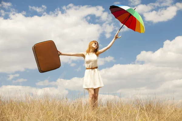 Красива руда дівчина з парасолькою і валіза на відкритому повітрі . — стокове фото