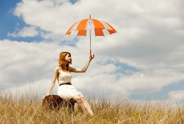 Hermosa chica pelirroja con paraguas y maleta al aire libre . —  Fotos de Stock