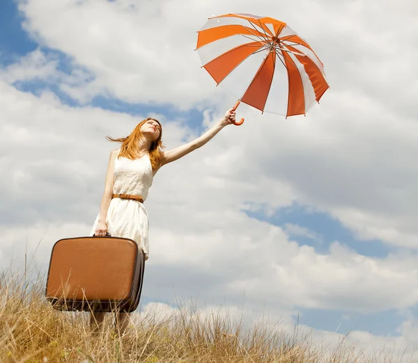 Mooi roodharig meisje met paraplu en koffer in buiten. — Stockfoto