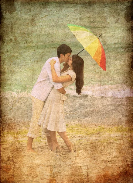 Pareja besándose bajo el paraguas en la playa — Foto de Stock