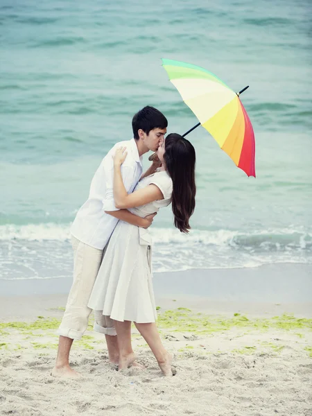 カップルはビーチでの傘の下でキス — ストック写真