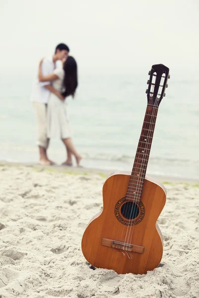 Couple kissing at the beach and guitar. — Stock Photo, Image