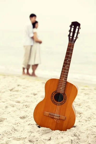 Pár líbání na pláži a kytara. — Stock fotografie