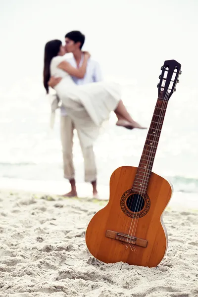 Para całuje na plaży i gitara. — Zdjęcie stockowe