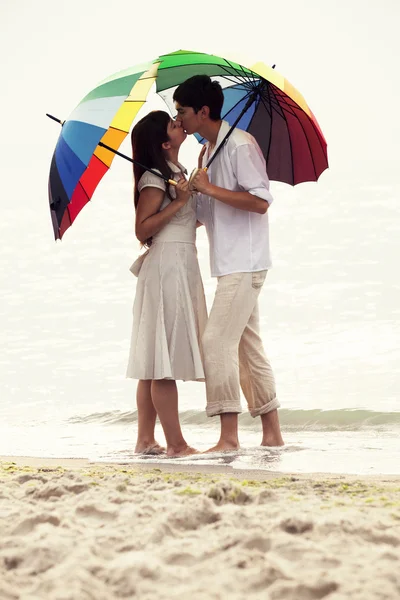 Paar küsst sich unter Sonnenschirm am Strand — Stockfoto