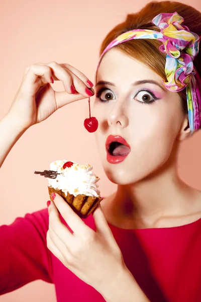 Stijl roodharige meisje met cake bij roze achtergrond. — Stockfoto