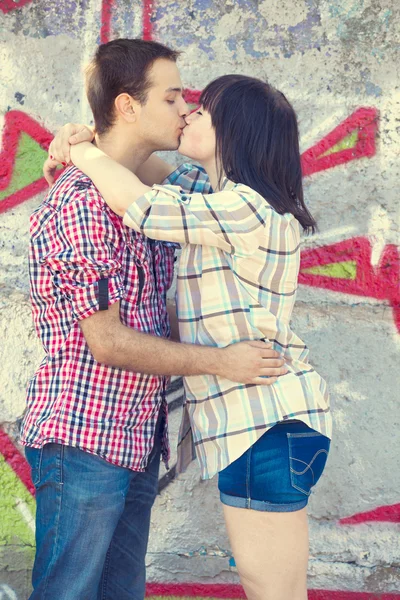 Giovane coppia baciare vicino graffiti sfondo . — Foto Stock