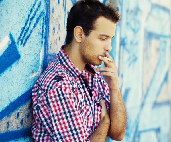Ung tonåring pojke röka nära graffiti wall. — Stockfoto