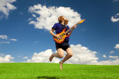 Redhead girl jumping with guitar at outdoor.