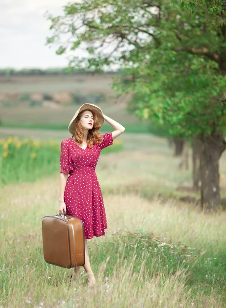 Rusovláska dívka s kufrem na venkovní. — Stock fotografie
