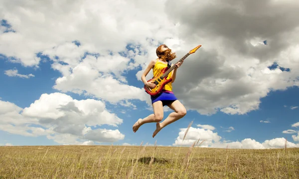 Rothaarige Mädchen springen mit Gitarre im Freien. — Stockfoto