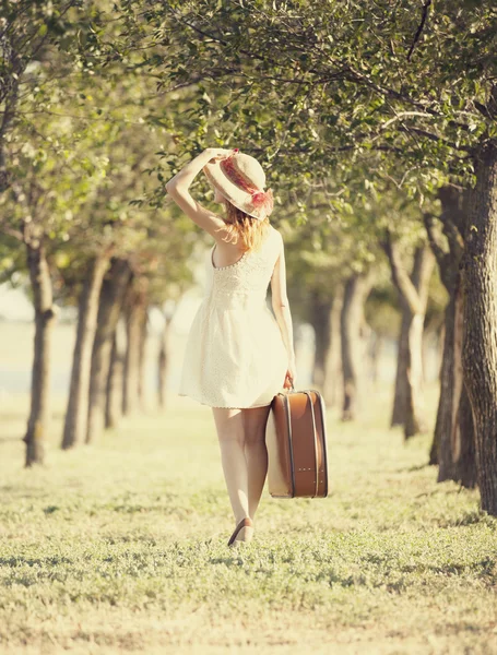 行李箱在树的巷子里的红发女孩. — 图库照片