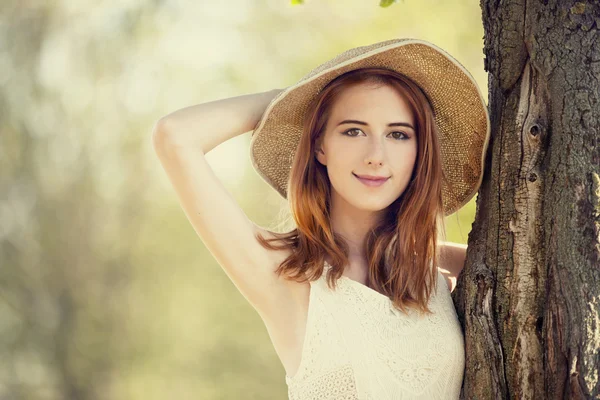 Κοκκινομάλλα κοπέλα με καπέλο κοντά δέντρο. — Φωτογραφία Αρχείου