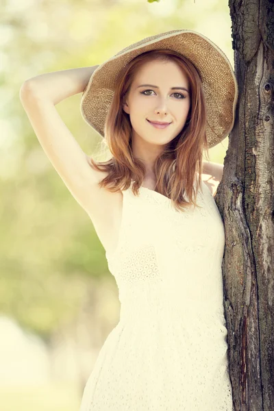 나무 근처 모자와 빨간 머리 소녀. — 스톡 사진
