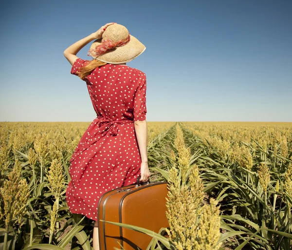 Рыжая девушка с чемоданом на кукурузном поле . — стоковое фото