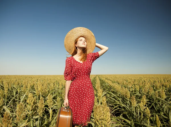 Vöröshajú lány a kukoricásban bőrönddel. — Stock Fotó