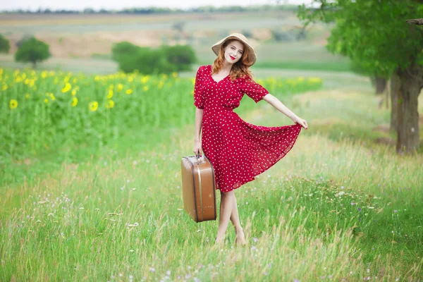 Rusovláska dívka s kufrem na venkovní. — Stock fotografie