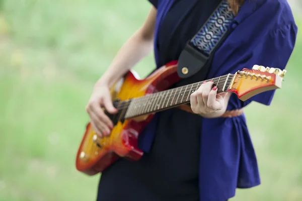 Närbild på gitarr i flickans händer på utomhus. — Stockfoto