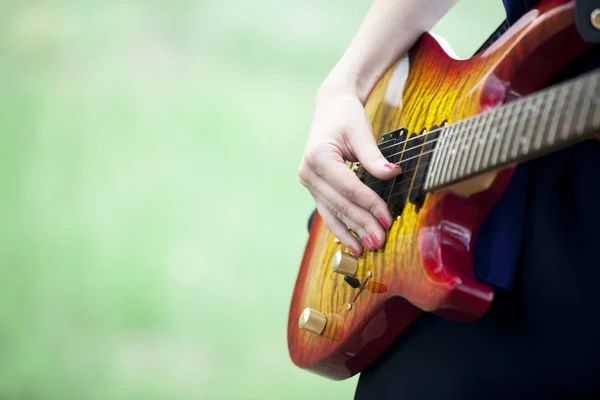 Крупним планом вид на гітару в руках дівчини на відкритому повітрі . — стокове фото