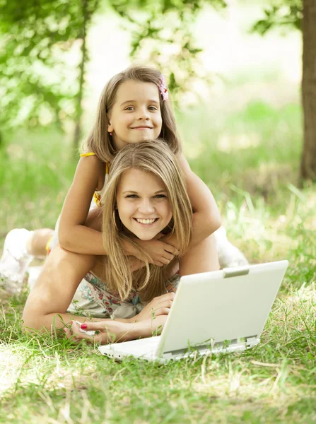 Two sisters with laptop in the park. — Stock Photo, Image