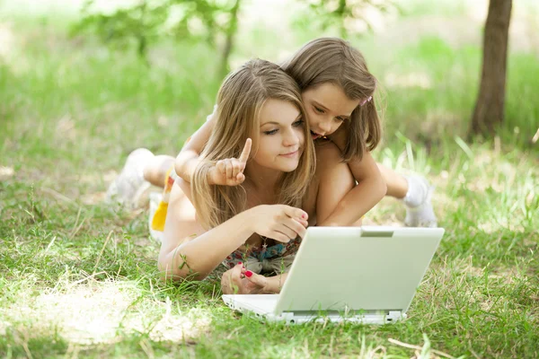 Two sisters with laptop in the park. — Stock Photo, Image