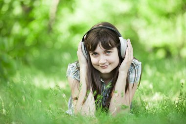 Yeşil bahar çimlerinde kulaklıklı genç bir moda kızı..