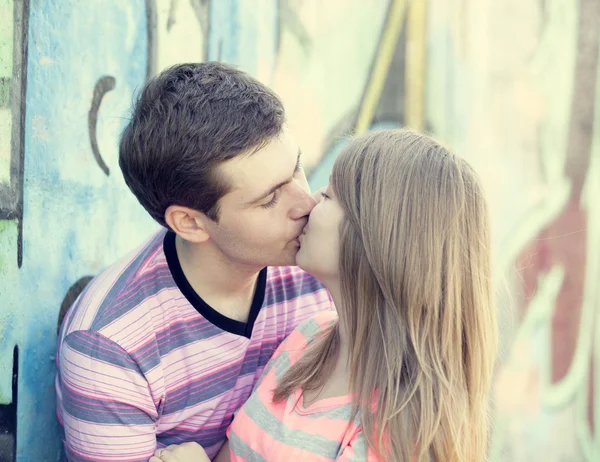 年轻情侣接吻附近涂鸦背景. — 图库照片