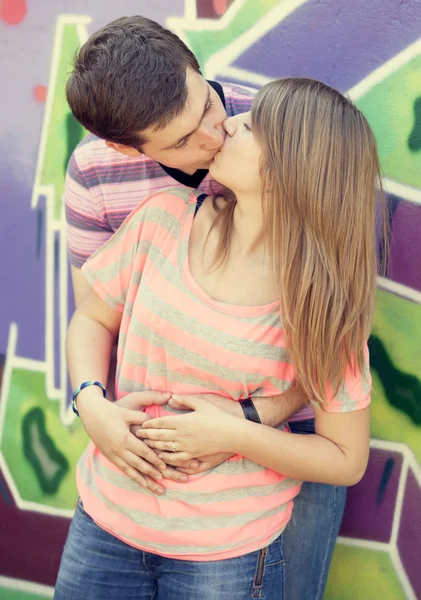 Junges Paar küsst sich in der Nähe von Graffiti-Hintergrund. — Stockfoto