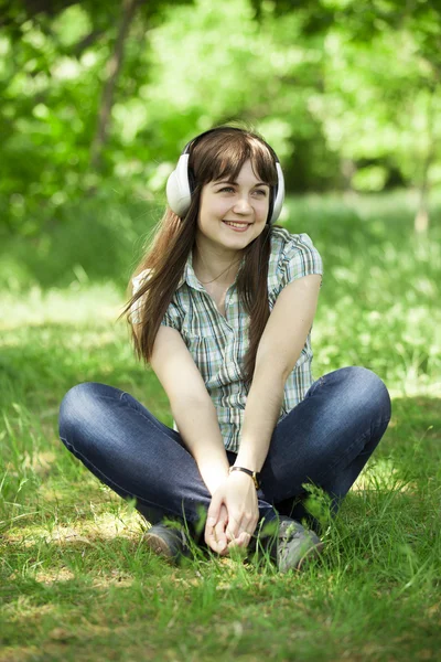 Chica de la moda joven con auriculares en la hierba verde primavera . — Foto de Stock