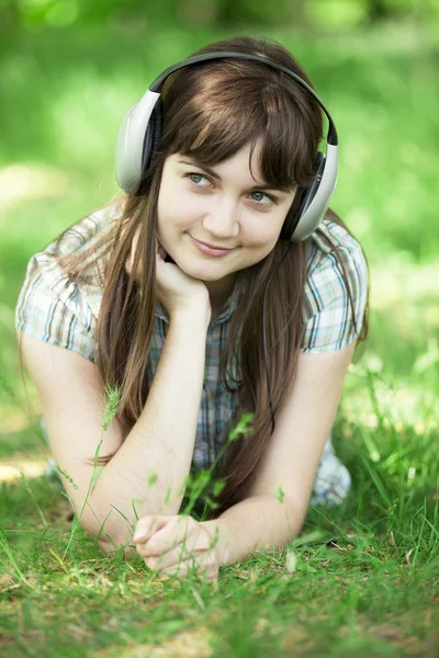 Fiatal divat lány fejhallgató zöld tavaszi fű. — Stock Fotó
