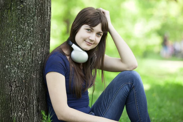 Young fashion girl with headphones at green spring grass. — Stock Photo, Image