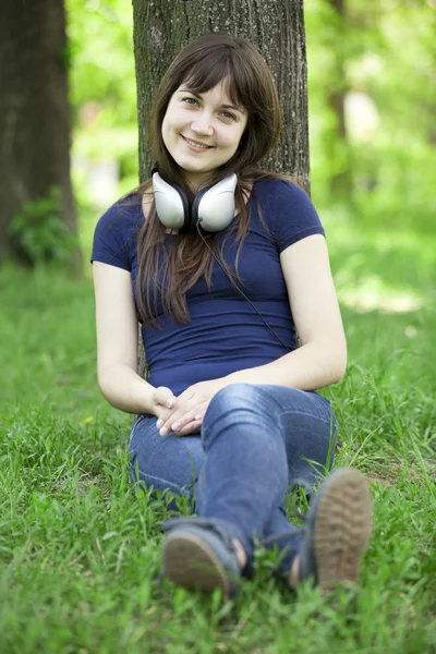 年轻时尚女郎，头戴耳机，绿色春草. — 图库照片