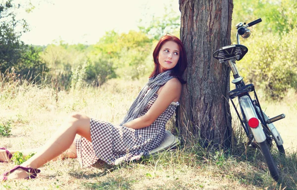 Mooi meisje zit in de buurt van fiets en boom in rust in bos. Pho — Stockfoto