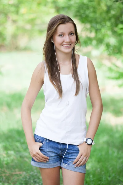 Красивая девушка-подросток в парке в наушниках . — стоковое фото