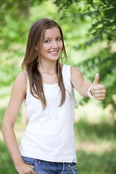 Mooie tiener meisje in het park met koptelefoon. — Stockfoto