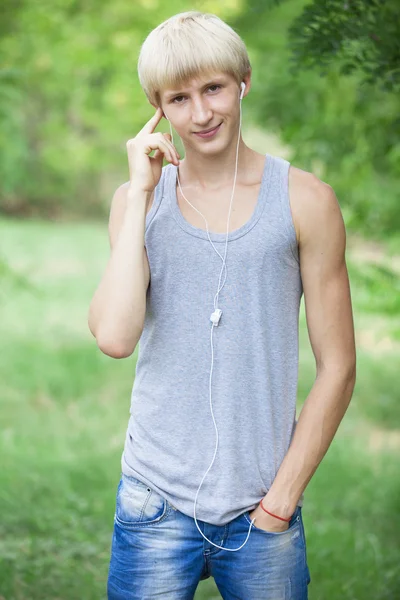 Tiener jongen met koptelefoon in park — Stockfoto