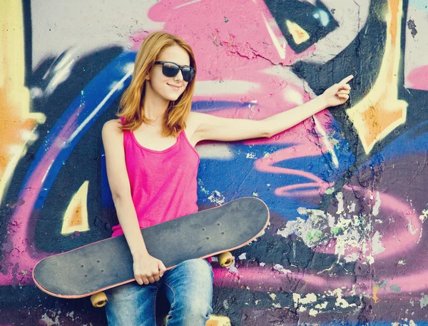 Style girl with skateboard near graffiti wall. — Stock Photo, Image