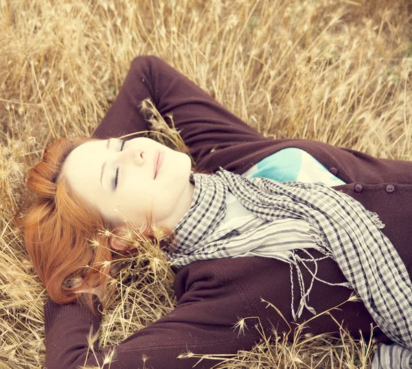 Piękna rudowłosa dziewczyna w żółty jesienią trawa. — Zdjęcie stockowe